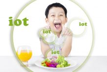 Cute little child making OK gesture while eating salad and juice, isolated on white background